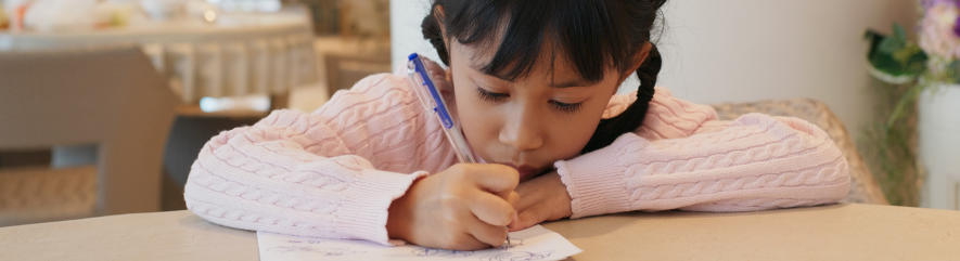 Girl drawing with pen while seated at table 