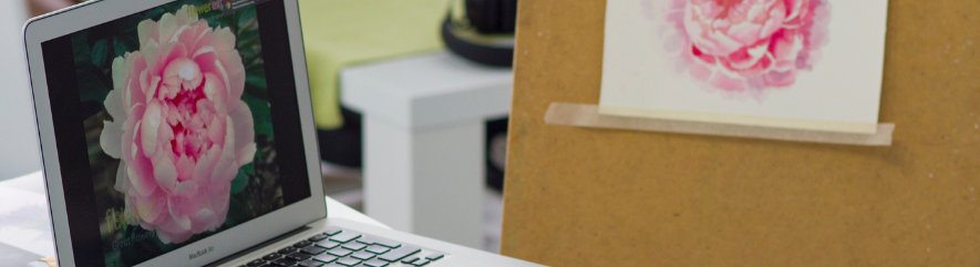 Laptop with flower image on screen, next to easel with sale flower image on paper