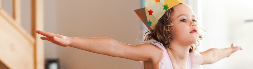 Little girl dancing inside wearing paper crown