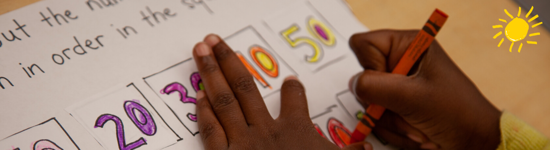A child's hand show them working coloring in a series of numbers with brightly-colored crayons